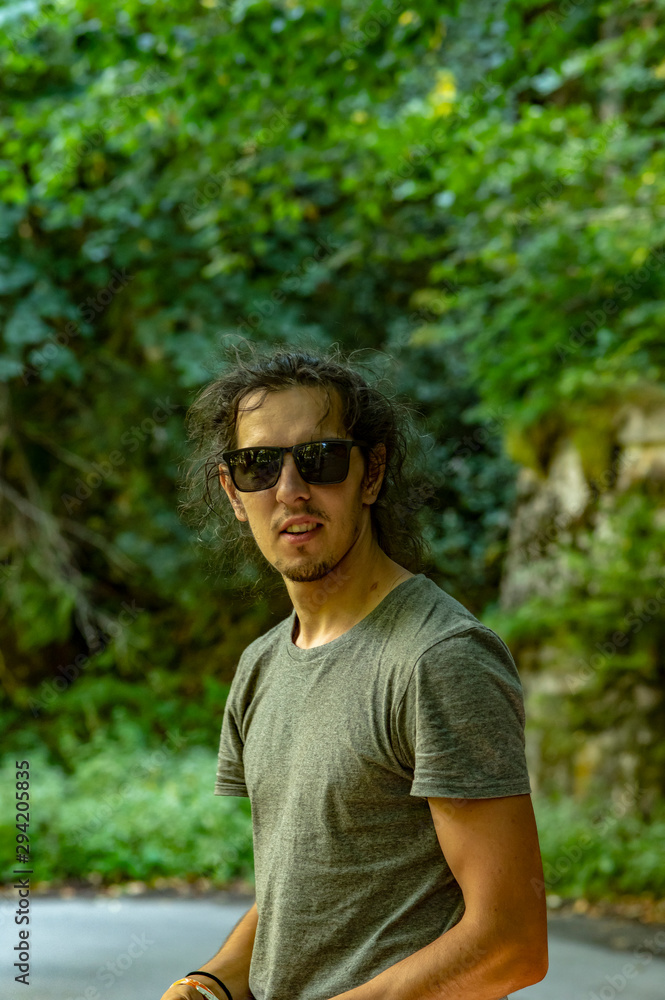 Walk in the fresh air. A young man with glasses looks at the nature around him. A man stands on the road. Walk in the fresh air. A young man with glasses looks at the nature around him. A man stands on the road.