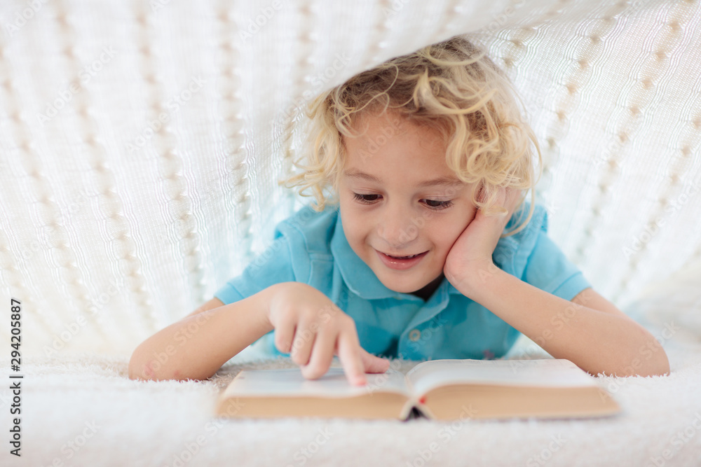 Fototapeta premium Child reading book in bed. Kids read books.