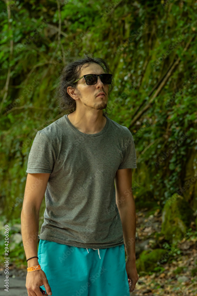 Walk in the fresh air. A young man with glasses looks at the nature around him. A man walks along the road. Walk in the fresh air. A young man with glasses looks at the nature around him. A man walks along the road.