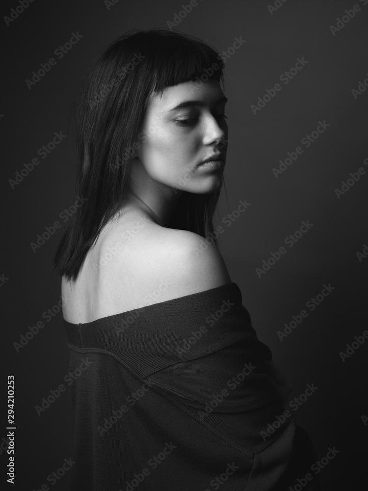 Portrait of sad young woman with bare shoulders. Black and white. From back