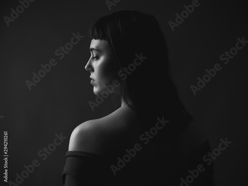 Portrait of sad young woman with bare shoulders. Black and white. From back