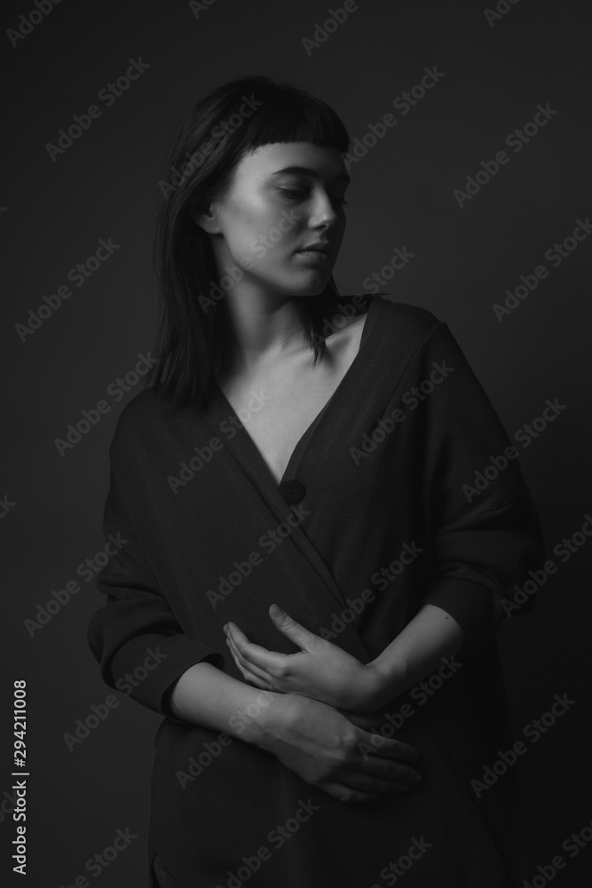 Classic portrait of young woman in studio. Black and white. Low key
