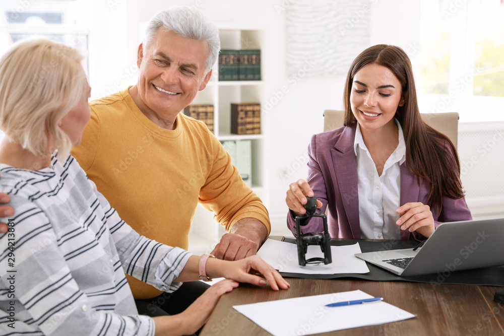 Female notary working with mature couple in office Female notary working with mature couple in office
