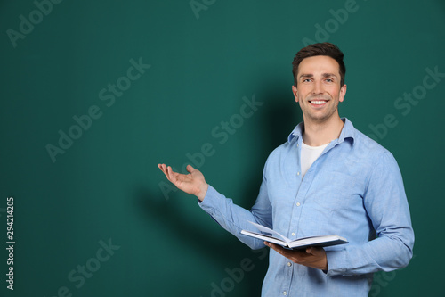 Portrait of male teacher with book on color background. Space for text photo