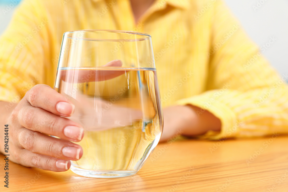 Woman holding glass of water at wooden table, closeup with space for text. Refreshing drink Woman holding glass of water at wooden table, closeup with space for text. Refreshing drink