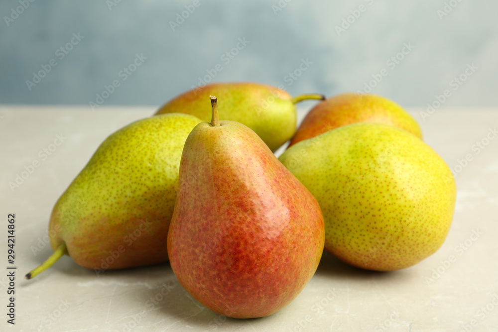Heap of ripe juicy pears on light stone table against blue background Heap of ripe juicy pears on light stone table against blue background