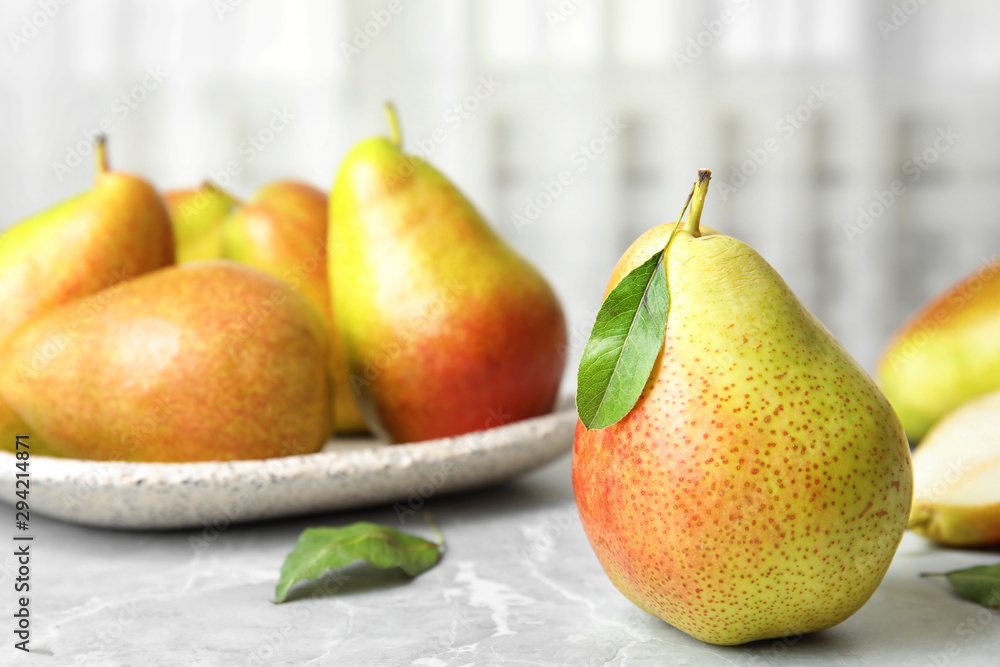 Ripe juicy pears on grey stone table against light background. Space for text Ripe juicy pears on grey stone table against light background. Space for text