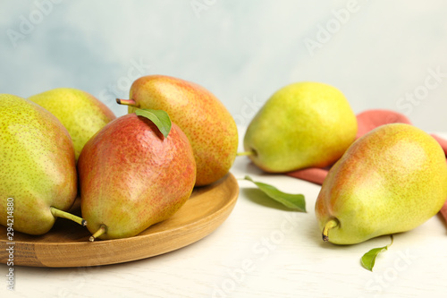 Ripe juicy pears on white wooden table against light background