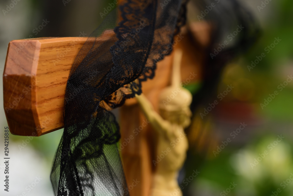 Close-up and background of a simple wooden cross in a Christian graveyard with a black ribbon