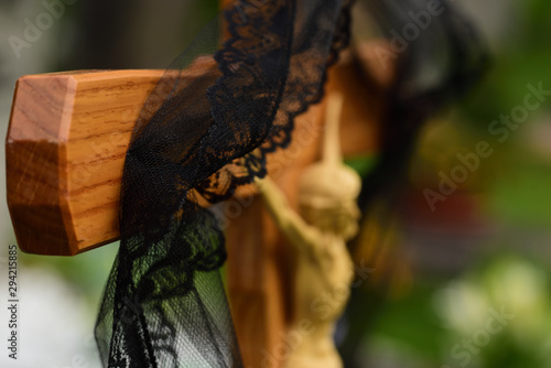 Close-up and background of a simple wooden cross in a Christian graveyard with a black ribbon