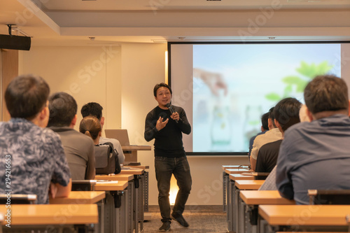 Asian Speaker is speaking on the stage over the presentation screen in the education seminar