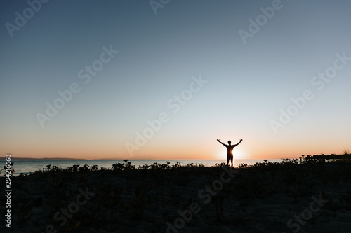 Silhouette of a young man enjoying beautiful sunset on the beach 