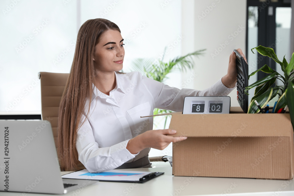 Happy young woman packing stuff in box at office Happy young woman packing stuff in box at office