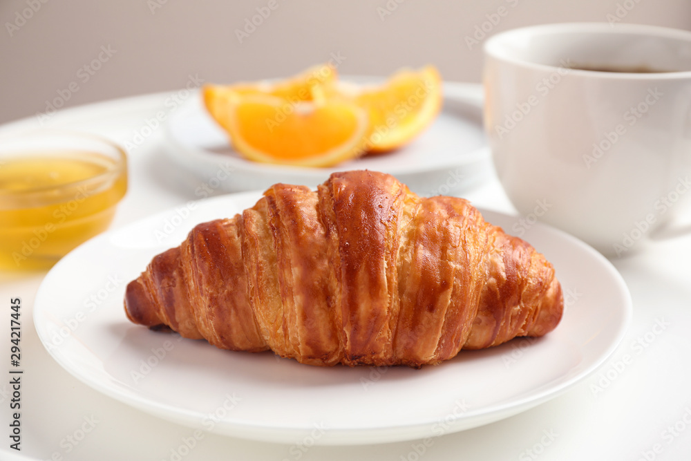 Delicious breakfast with croissant and honey on white table, closeup