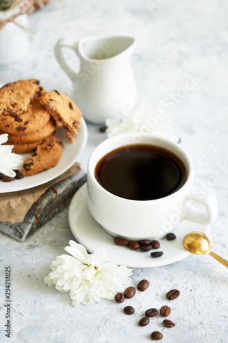 Cup of black strong coffee with coffee beans and cookies on white background