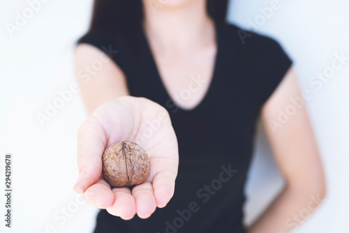 Detail of young woman   s hand  holding a handful of organic walnut. Selective focus