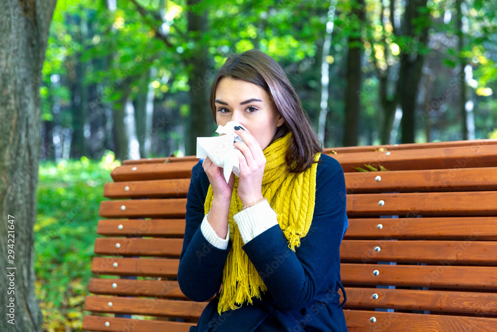 Woman blowing nose with tissue paper at park Woman blowing nose with tissue paper at park