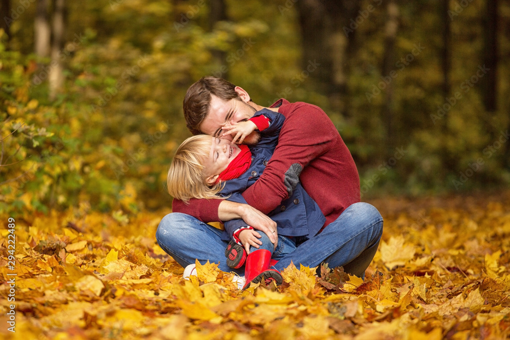 Father and daughter hug and laugh in the autumn park.