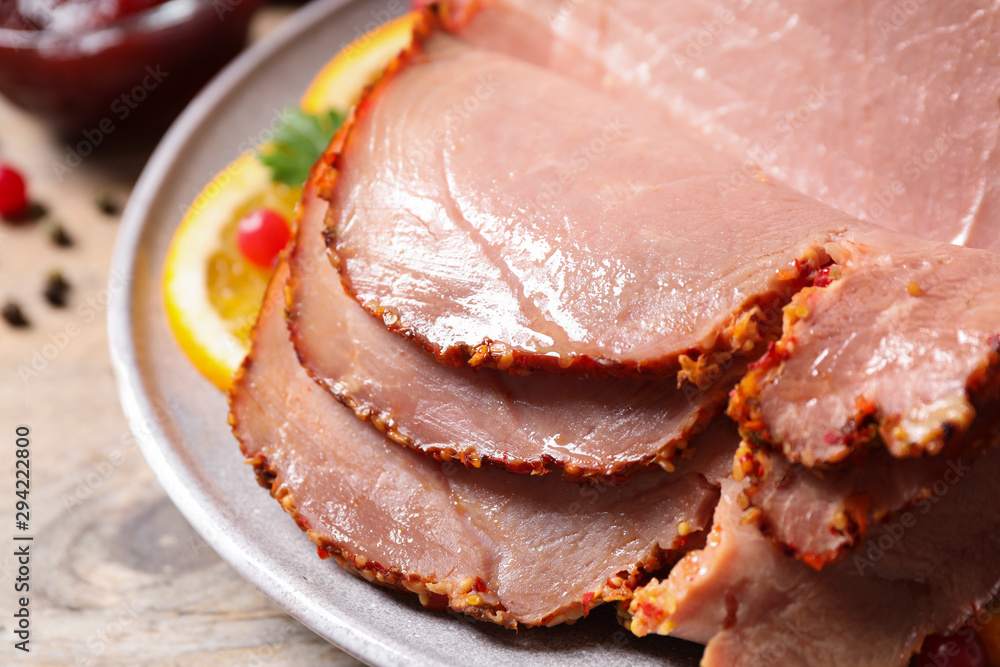 Delicious ham served with garnish on wooden table, closeup