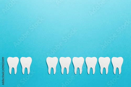 Prosthetic dentistry. White tooths on blue background. Oral dental hygiene. Dental health concept. Oral care, teeth restoration. Dentist day concept. Flat lay. Top view. Pastel colors