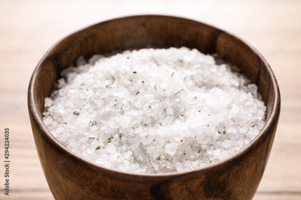 White sea salt for spa scrubbing procedure on wooden table, closeup