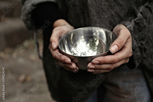 Poor homeless woman with empty bowl outdoors, closeup