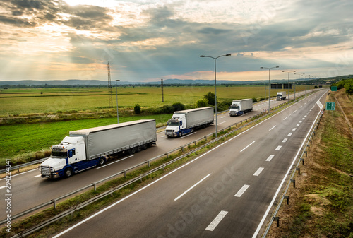 Bilde på lerret Lorry trucks in line as a caravan or convoy  on country highway under a beautifu