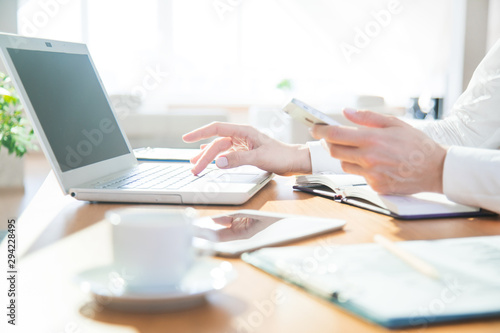 Hands of businesswoman  working with laptop and phone in office
