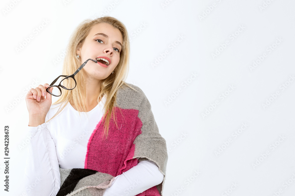 Young blond woman with glasses wrapped in a wide scarf posing on a white background Young blond woman with glasses wrapped in a wide scarf posing on a white background