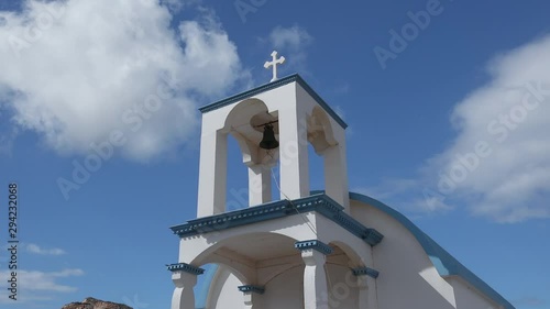 Close-up of Ekklisia Agios Spiridon church near Seitan Limania Stefanou beach on Crete island. Beautiful chapel with bell and traditional blue roof with cross. Ancient holy landmark in Greece photo