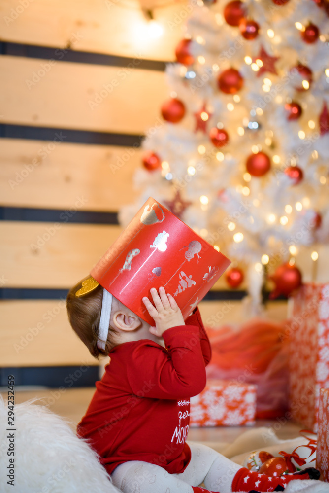 Child toddler crawling to gifts lying under Christmas tree