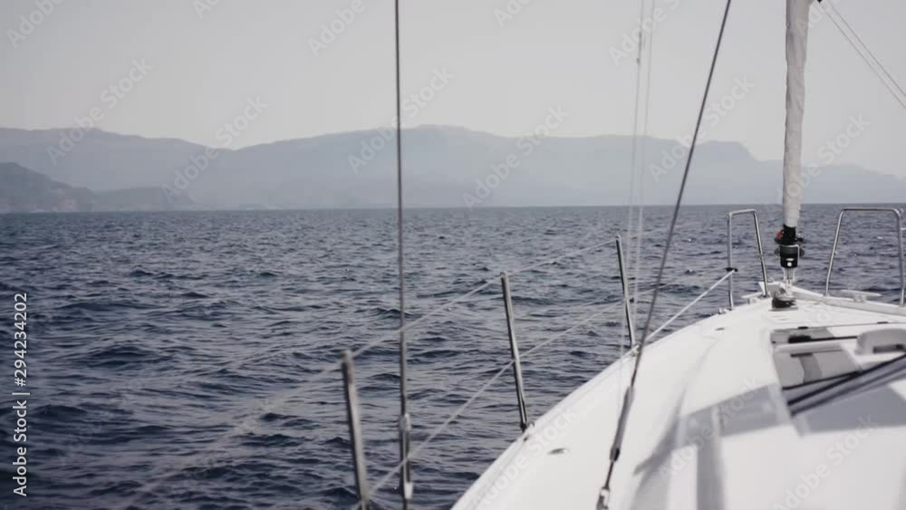 Someone is standing on front deck of white sailing yacht, enjoying gorgeous view of the Mediterranean Sea. Someone is standing on front deck of white sailing yacht, enjoying gorgeous view of the Mediterranean Sea.