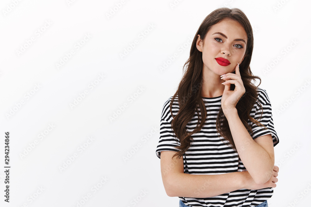 Sassy good-looking modern woman with red lipstick, striped t-shirt, listen interesting idea, touch chin smiling pleased, tilt head amused, watching curious show, thoughtful stand white background Sassy good-looking modern woman with red lipstick, striped t-shirt, listen interesting idea, touch chin smiling pleased, tilt head amused, watching curious show, thoughtful stand white background