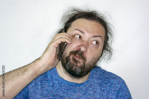 Strange and funny middle-aged man with an exaggeratedly skeptical expression on his face speaks on the phone