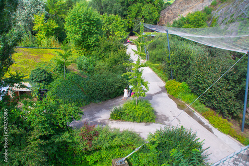 Top view of the green mountainside, paths and protective nets