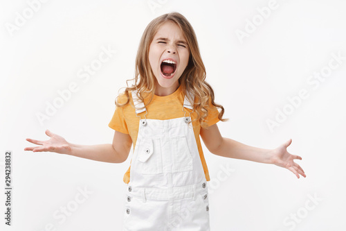 Angry little child, girl shouting out loud misbehave, arguing hate everyone standing pissed annoyed unfair treatment, whining showing bad temper, stand white background moody