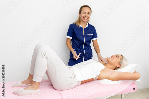 client beauty salon lying on the couch and next to her is a girl cosmetologist. they're preparing for the procedure. preparation for the procedure of hair removal. girls smile