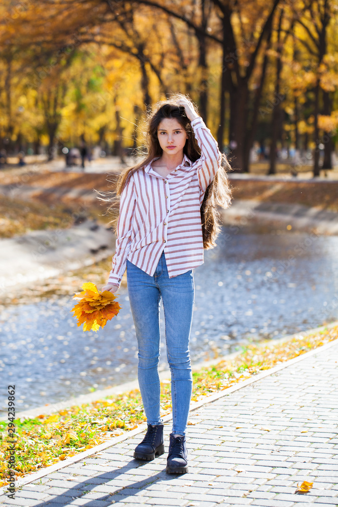 Pretty brunette little girl posing in autumn park background Pretty brunette little girl posing in autumn park background