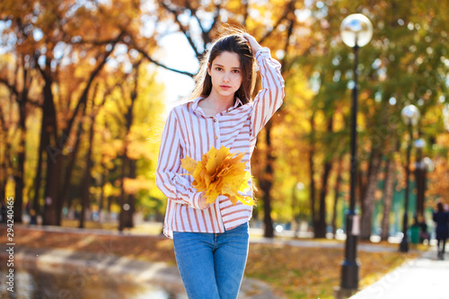 Pretty brunette little girl posing in autumn park background