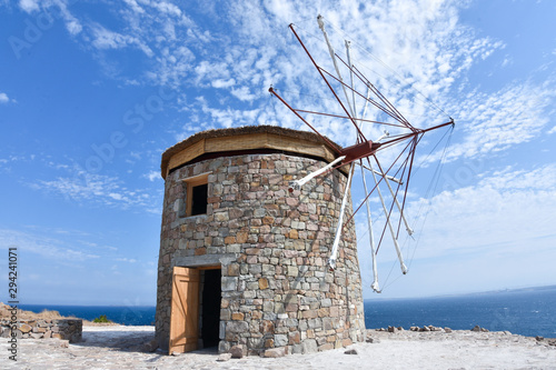 Old windmill under cloudy blue sky.