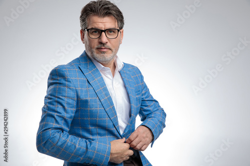 businessman sitting and fixing his jacket while looking at camera photo