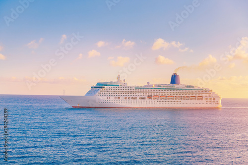 Fototapeta Naklejka Na Ścianę i Meble -  Luxury cruise ship leaves port sunset in blue sea with clouds