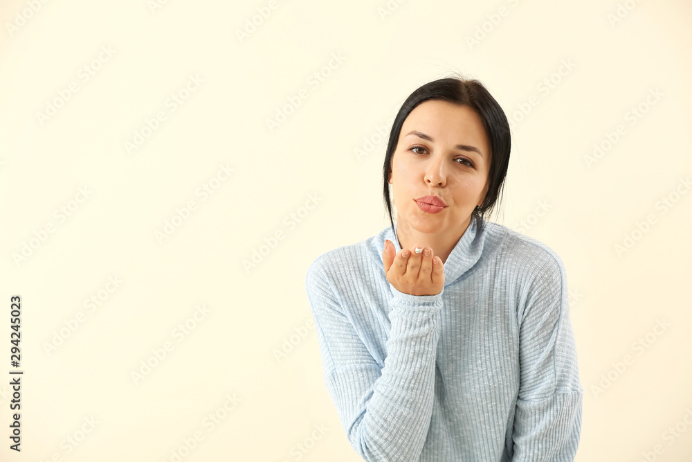 Portrait of beautiful woman blowing kiss on light background Portrait of beautiful woman blowing kiss on light background