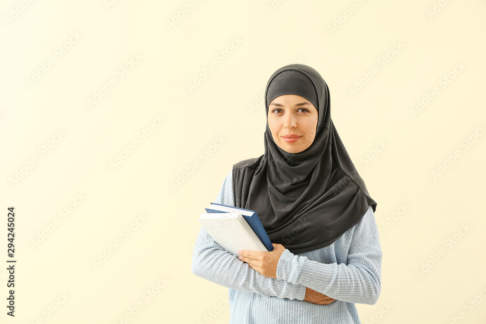 Portrait of Muslim woman with books on light background Portrait of Muslim woman with books on light background