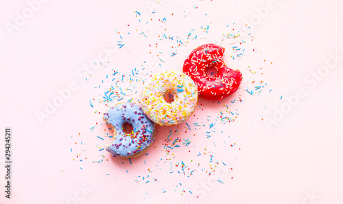 Bitten colored donuts  with colorful sprinkles on pink background. Copy space