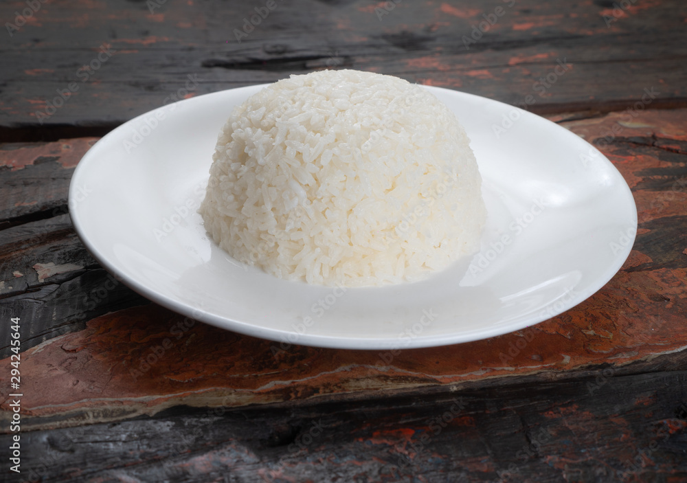 Jasmine steamed rice on the white plate isolated on rustic wooden kitchen table