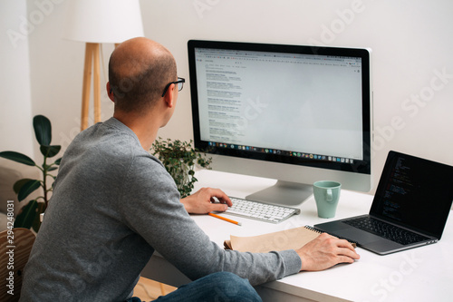 Fotografie Programmer, working behind the desk, googling and coding at the same time