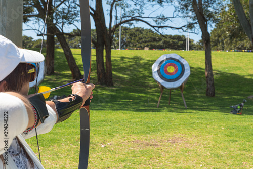 sport woman aiming at a archery target in a park