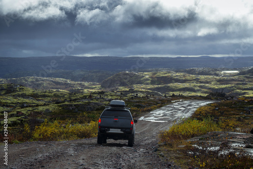 Off-road car on the stoned road in the tundra at rain weather photo