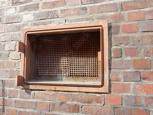 Tableau sur toile Old metal hatch of a coal shaft in a red brick wall out of order
